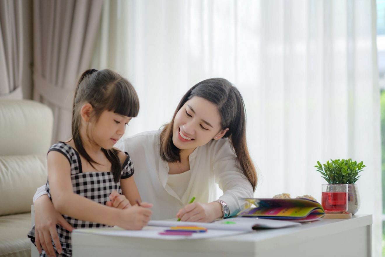 Modern mother joining homework together with daughter, happy time in living home and comfortable feel free