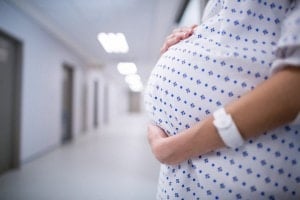 Mid section of pregnant woman standing in corridor of hospital