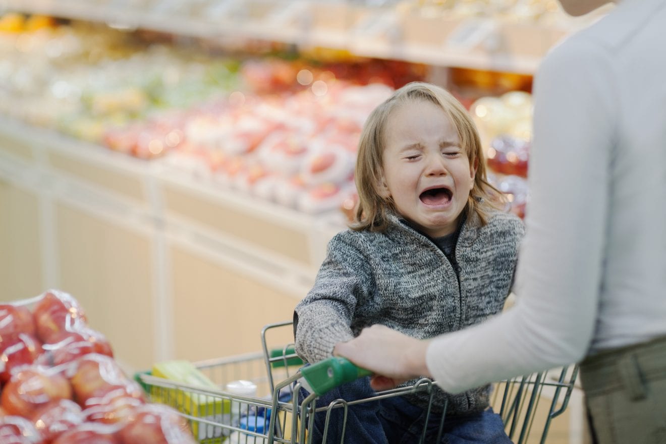 Child crying in shopping cart in supermarket