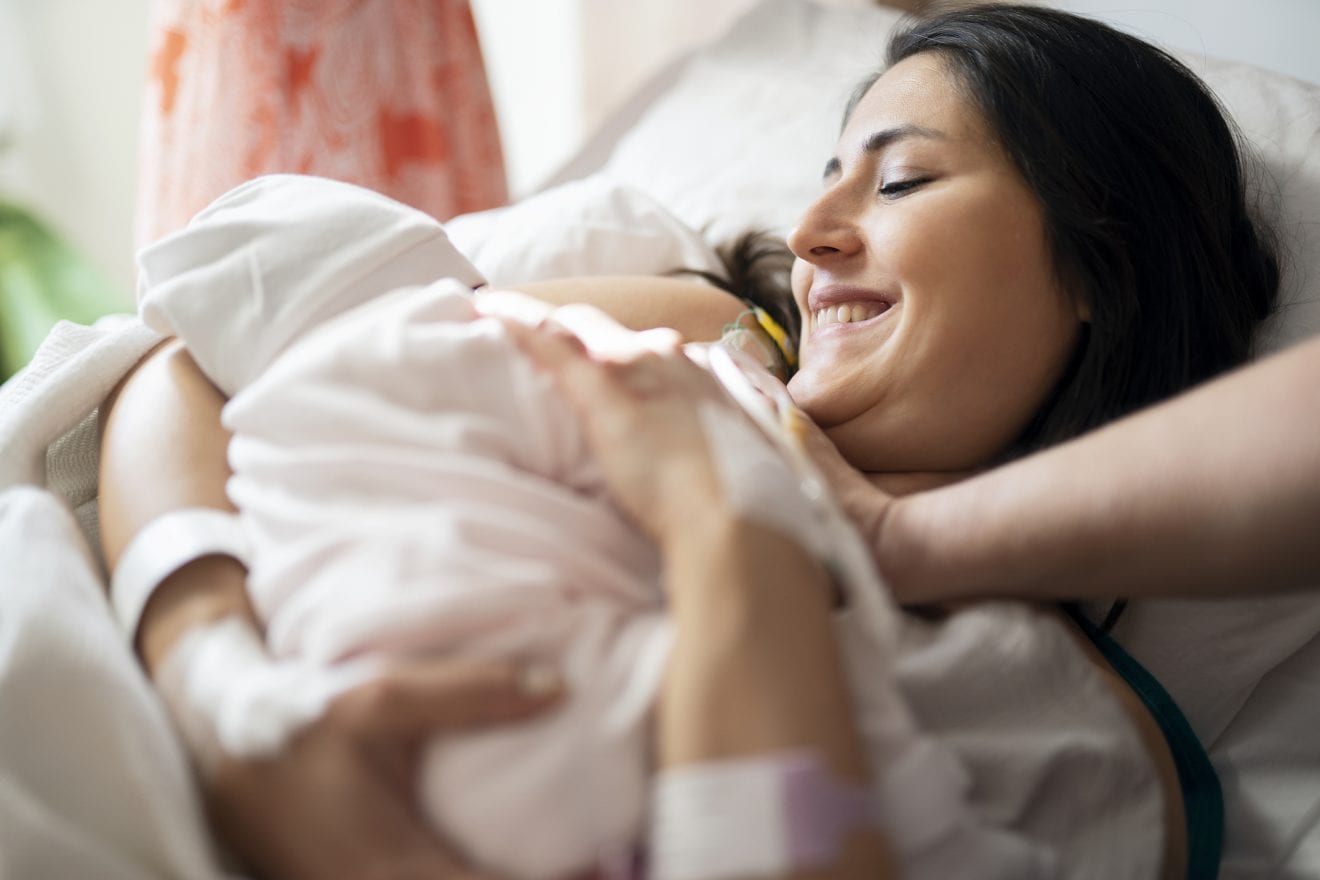 New mother breastfeeding her newborn baby in a hospital ward.