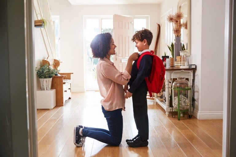 Mother At Home Getting Son Wearing Uniform Ready For First Day Of School
