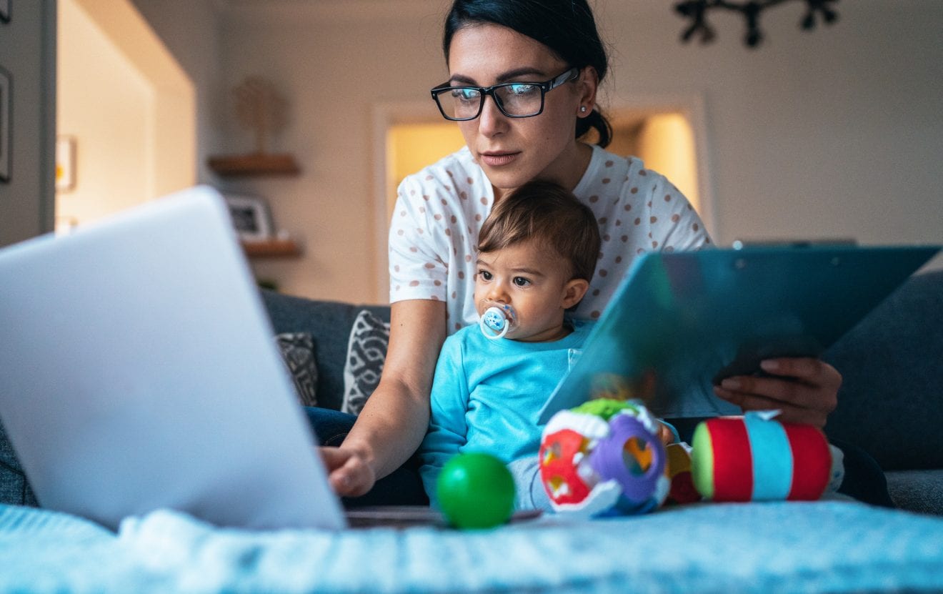 Young modern mother with a baby using laptop at home.