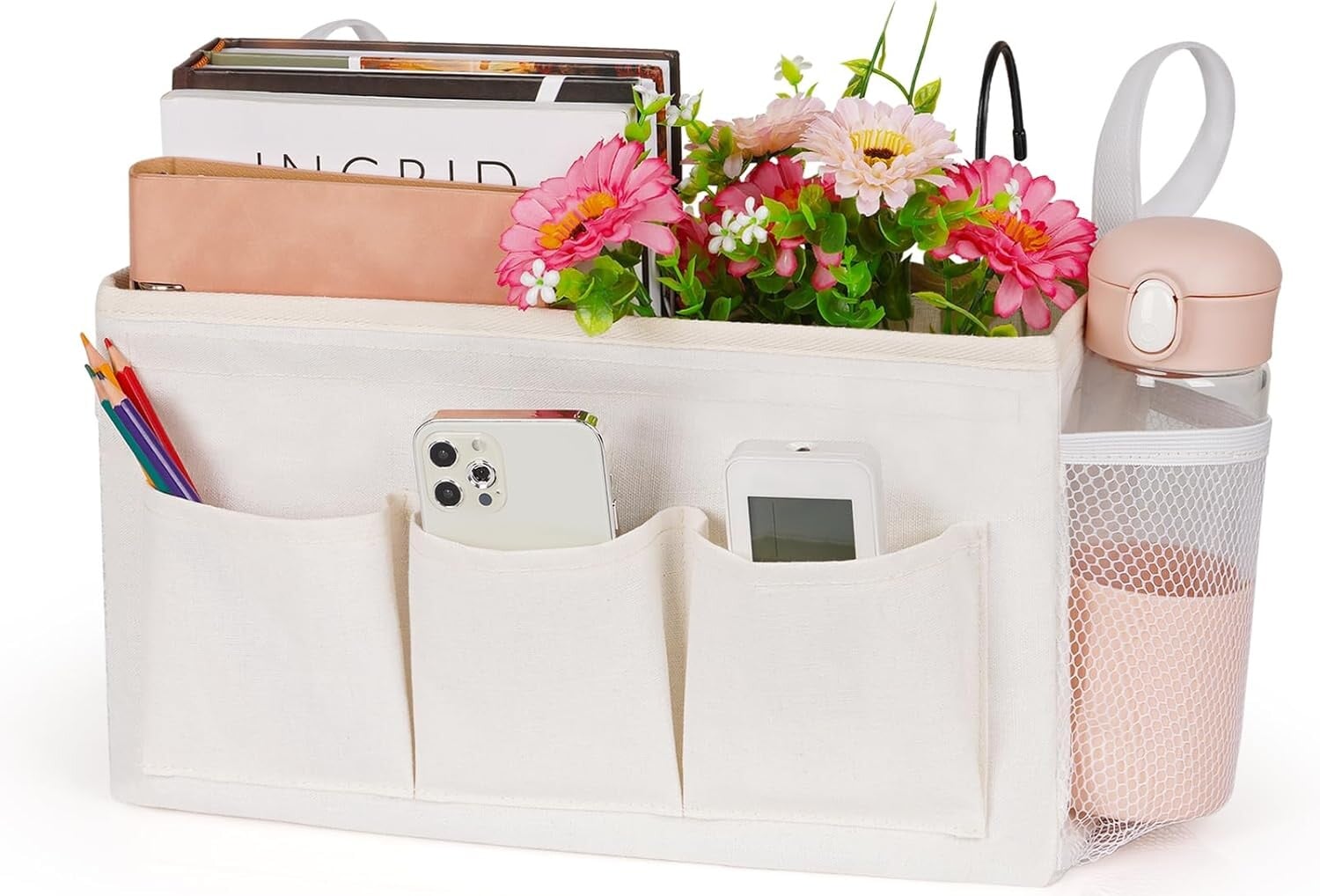 A cream-colored storage organizer with multiple pockets holds books, pencils, a smartphone, a calculator, and pink flowers&mdash;ideal for someone on bed rest. A pocket on the right contains a pink water bottle, making it a thoughtful addition to any care package.