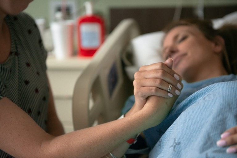 A woman holds the hand of a support person while in the throws of labor and trying to work through the pain of contractions.