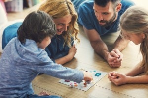 Family With Two Children Playing Board Game on The Floor At Home