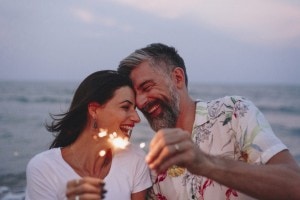 Couple celebrating a summer date night together with sparklers at the beach.