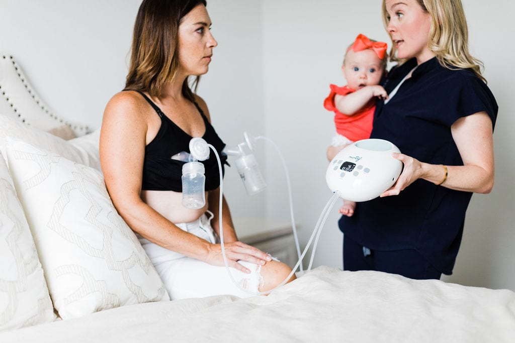 Postpartum doula holding the Motif Luna breast pump and baby while she explains things to her doula client.