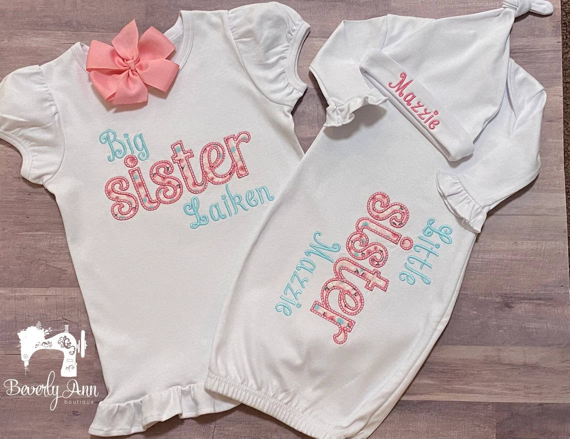 Two sets of baby clothes on a flat surface. The left outfit features Big sister Laiken in blue and pink letters with a pink bow. The right set includes a gown with Little sister Mazzie, a matching hat with Mazzie, perfect as coming home outfits. Logo reads BeverlyAnn Boutique.