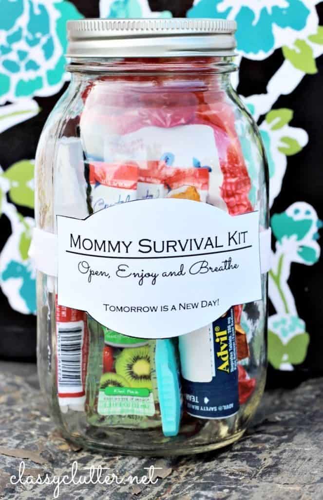 A glass jar labeled Mommy Survival Kit, perfect as a gift to bring a new family, filled with small essentials like a mini Advil pack, toothbrush, and snacks. The label reads Open, Enjoy and Breathe. Tomorrow is a new day! against a charming floral background.