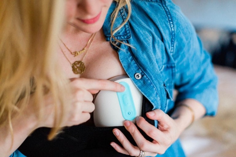 Woman turning on her wearable Willow breast pump.