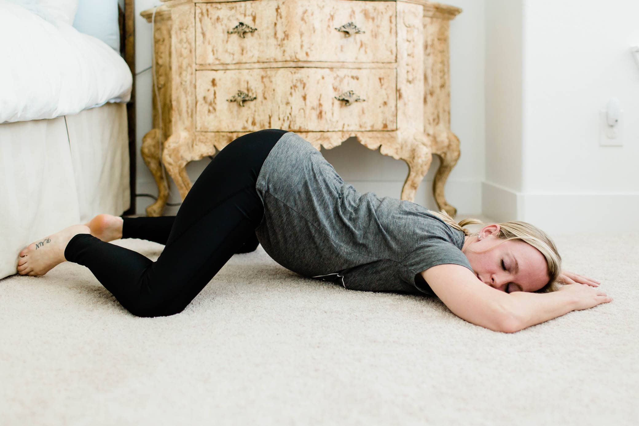 Pregnant woman doing open knee chest position on the floor.