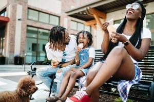 A cute young African American family enjoys relaxation time in the city with ice cream cones on a hot summer day.