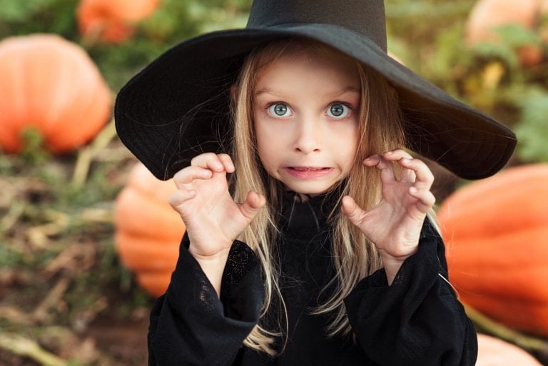 Cute little witch doing scary face. Halloween theme.