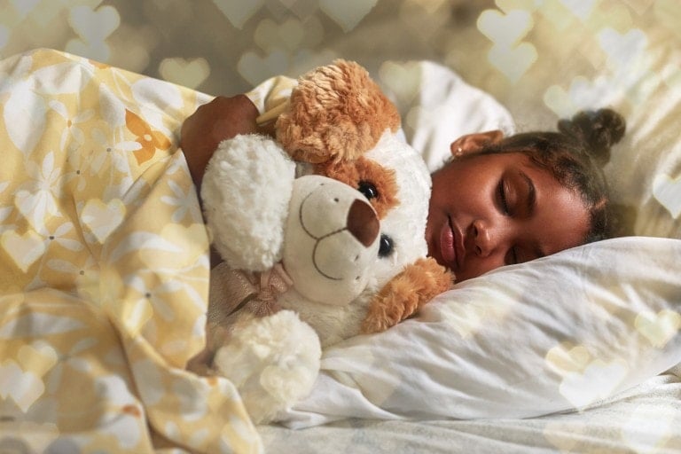 Shot of an adorable young girl sleeping peacefully in her bed cuddled up with her stuffed animal.