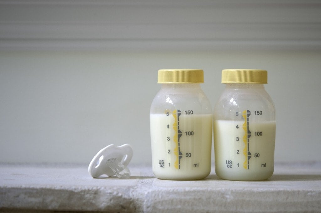 2 bottles of pumped breast milk with a pacifier