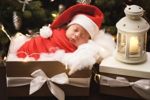 Cute newborn baby wearing Santa Claus hat is sleeping in the xmas gift box.
