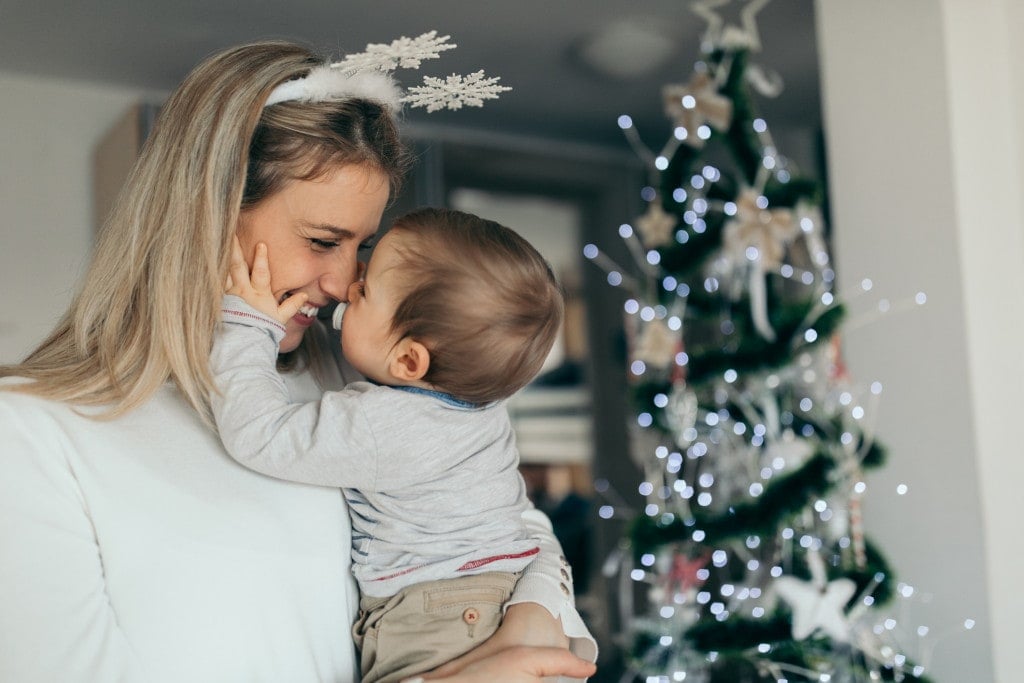 Happy mother holding her baby celebrating Christmas at home