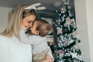 Happy mother holding her baby celebrating Christmas at home