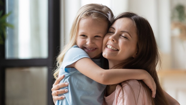 Happy little girl hug cuddle with excited young mother show care and love, smiling small preschooler daughter embrace overjoyed mom share tender sweet family moment together.