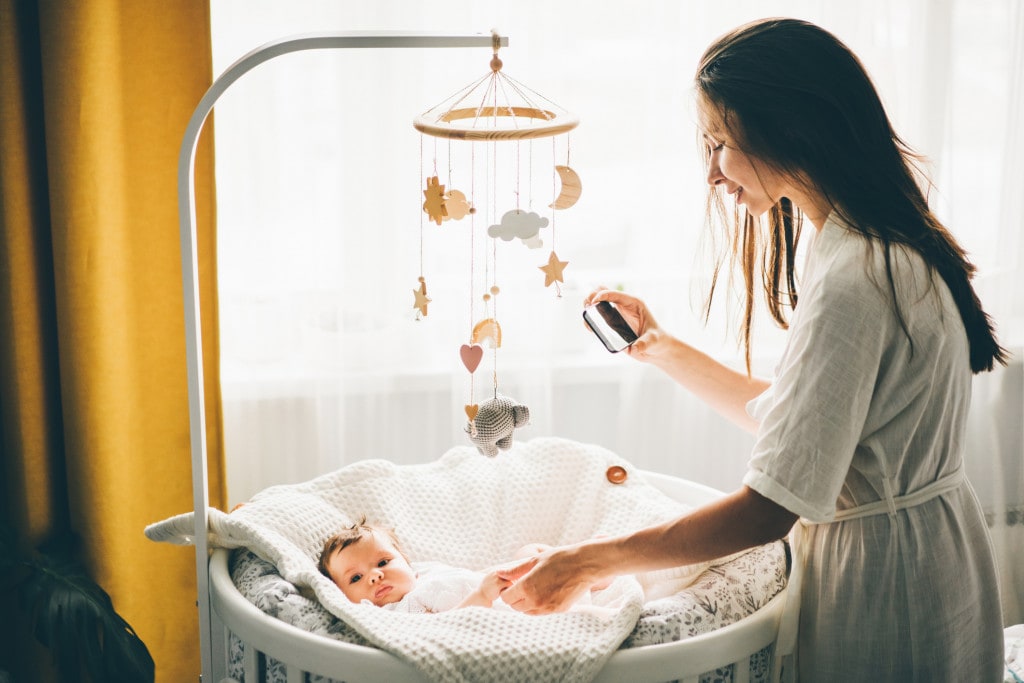 Mother taking a picture of her baby with a mobile phone.