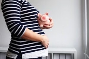 Pregnant woman with piggy bank in the office