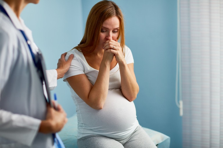 Pregnant woman crying with her doctor near by.