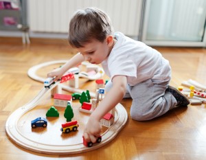 Little boy playing with wooden train set