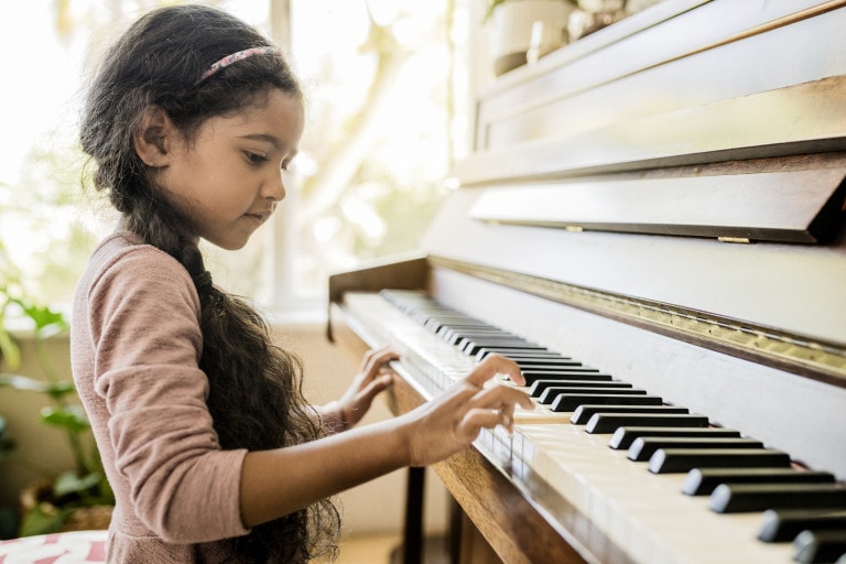 Side view of a girl playing the piano.