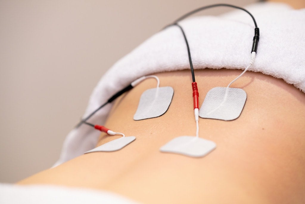 Electro stimulation in the lumbar zone in physical therapy to a young woman in a physiotherapy center.