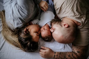Family with one child laying on bed, enjoying day at home