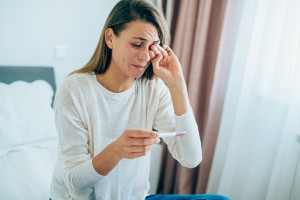 Woman crying while looking at pregnancy test.
