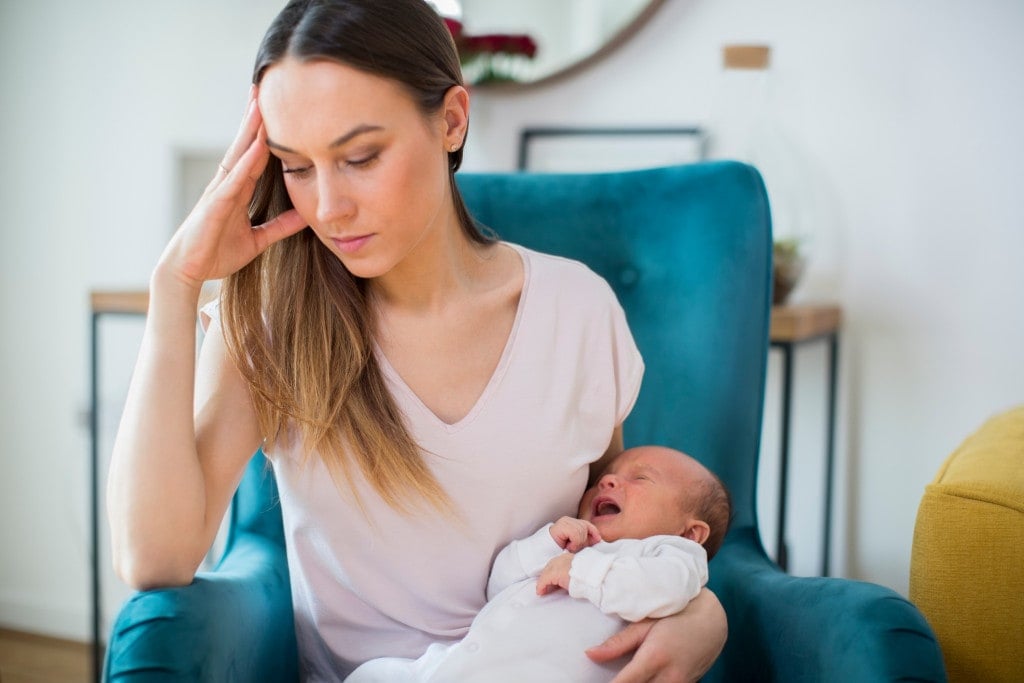 Stressed Mother Holding Crying Baby Suffering From Postpartum Depression At Home