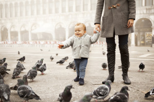 Boy playing with pigeons in Venice