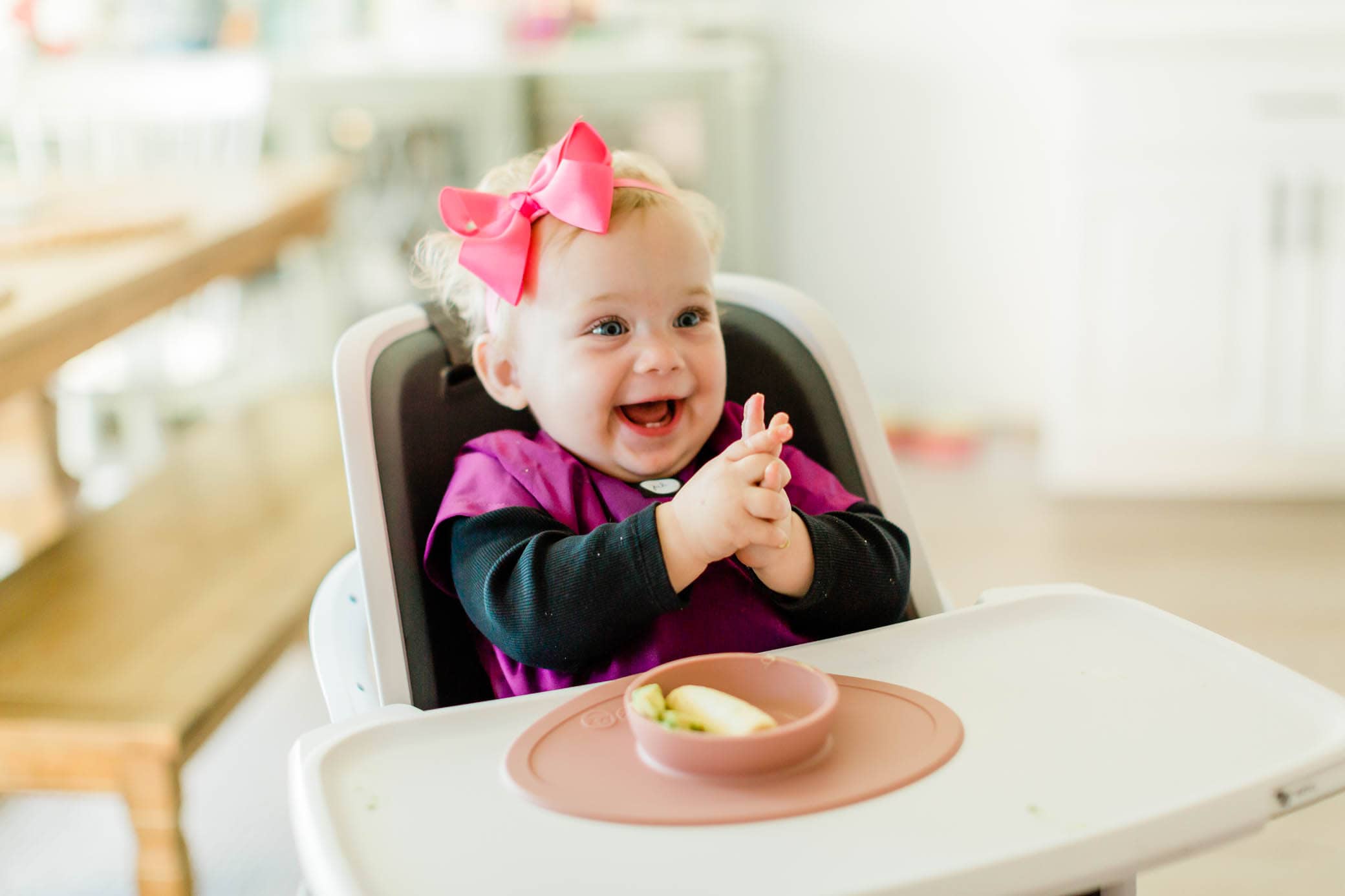 Happy baby girl sitting in her highchair about to start mealtime.
