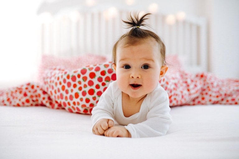 Adorable baby girl is lying in the bed