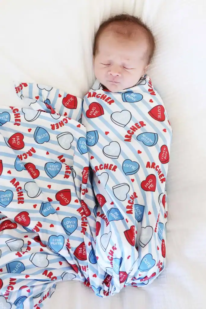 Adorable sleeping baby in Valentine's Day-themed outfit with hearts and love messages.