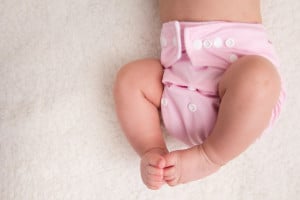 Baby laying down wearing a pink cloth diaper