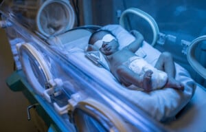 Beautiful latin american newborn baby in incubator getting treated for jaundice