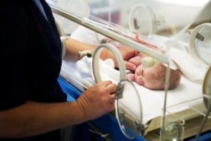 Nurse attends to a newborn baby girl in a hospital incubator.