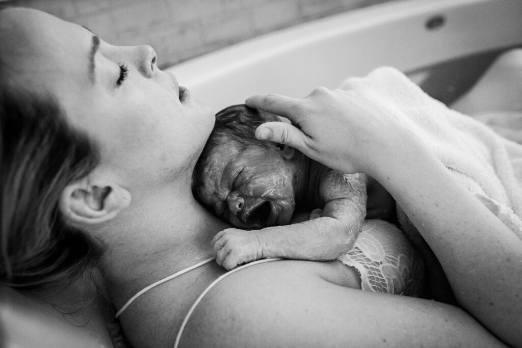 A woman holding her new baby after giving birth in the water.