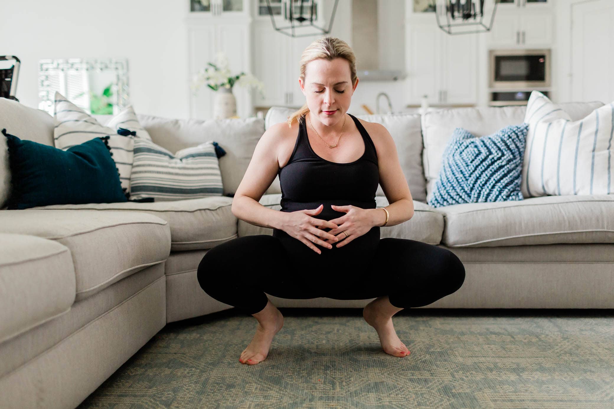 Pregnant woman in a squat position holding her belly