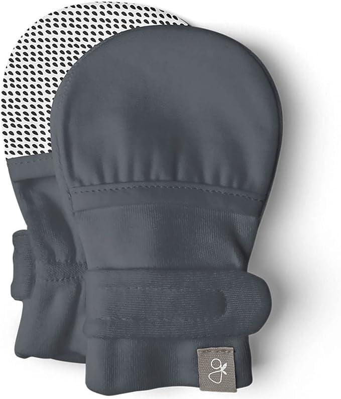 A pair of dark gray baby mittens with a Velcro strap, perfect for NICU gifts. One mitten is flipped to reveal the dotted grip pattern on the palm, and theres a small tag with a decorative letter on the wrist.