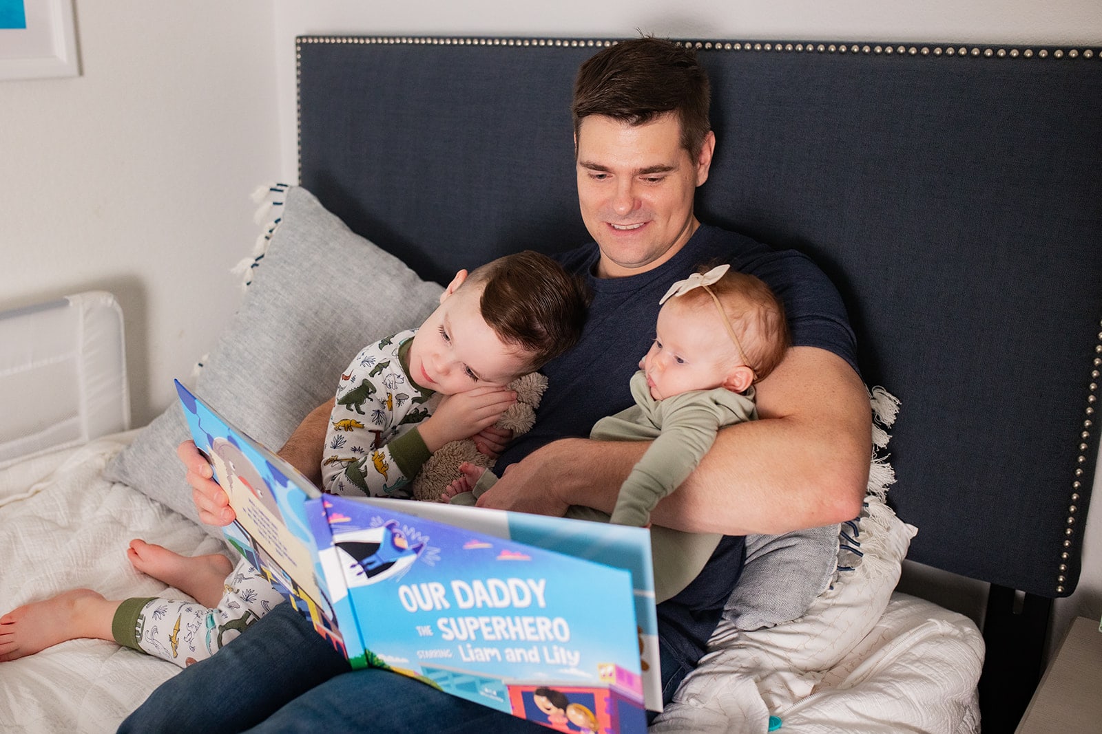 A father sitting in bed with his two kids reading them a bedtime story.