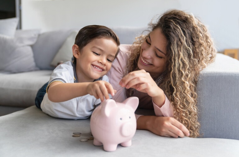 Portrait of a happy mother and son saving money in a piggybank and smiling