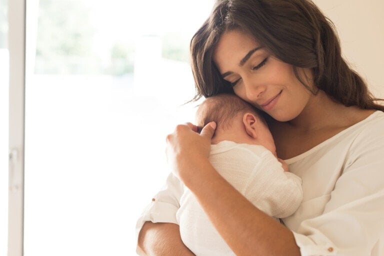 Pretty woman holding a newborn baby in her arms