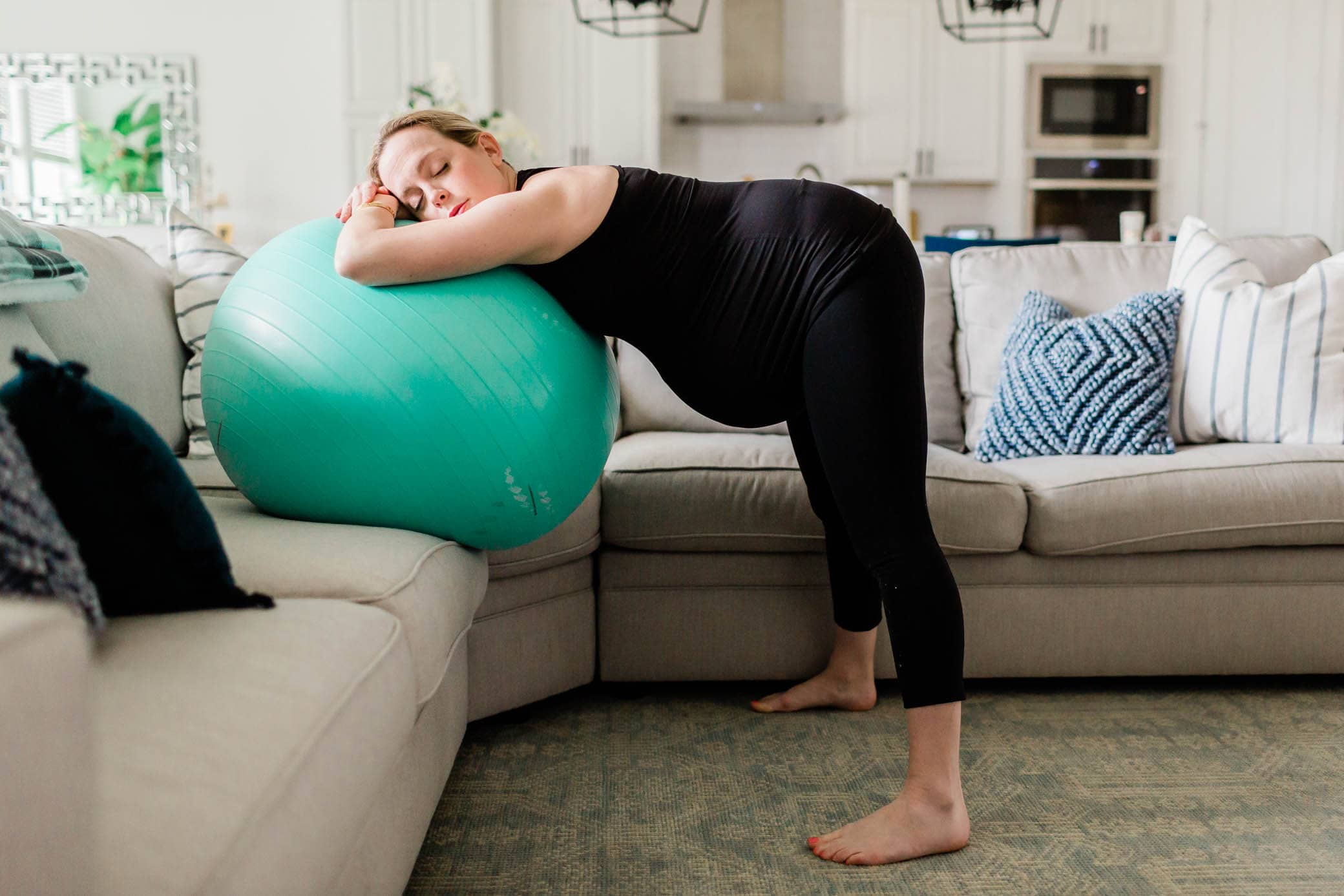 Pregnant woman standing up and leaning over on a birthing ball.