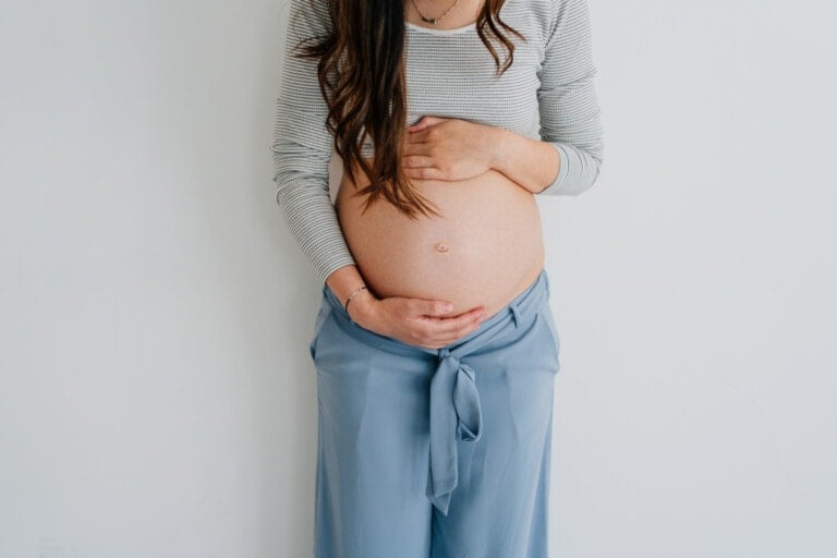 Portrait of a pregnant woman and her growing belly isolated on a white background.