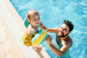 Cute little girl having fun with parents in pool.