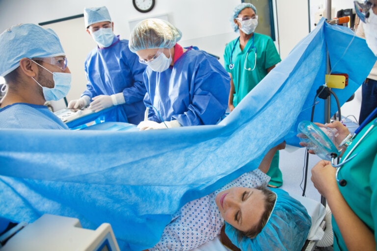 Surgical team performing Cesarean section on pregnant woman.
