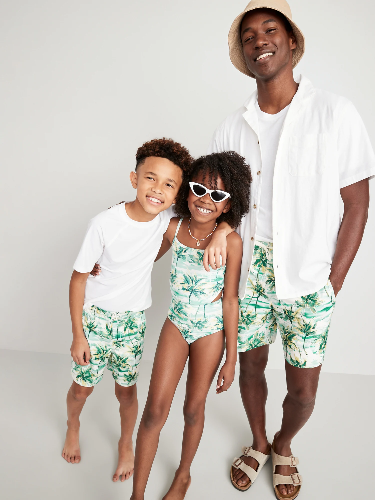 Dad with two kids in matching palm print bathing suits 
